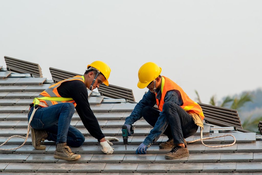 roofer using air pneumatic nail gun installing concrete roof tile top new roof 1